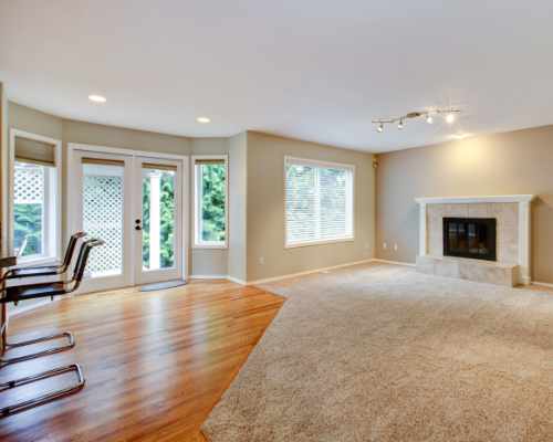 Kitchen with wood flooring and carpeted living room with fireplace