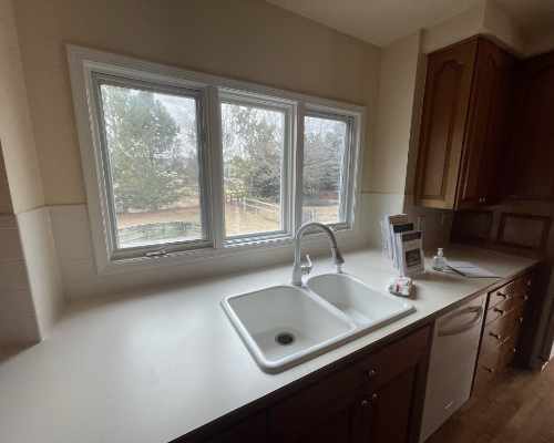 Kitchen with white laminate countertops, dishwasher and wooden cabinets