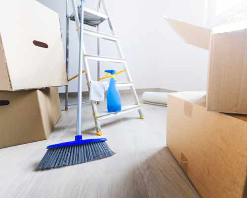 Moving boxes and cleaning supplies in room without furniture