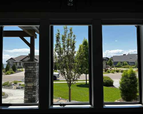 Three boxed windows facing shrubbery and neighboring homes